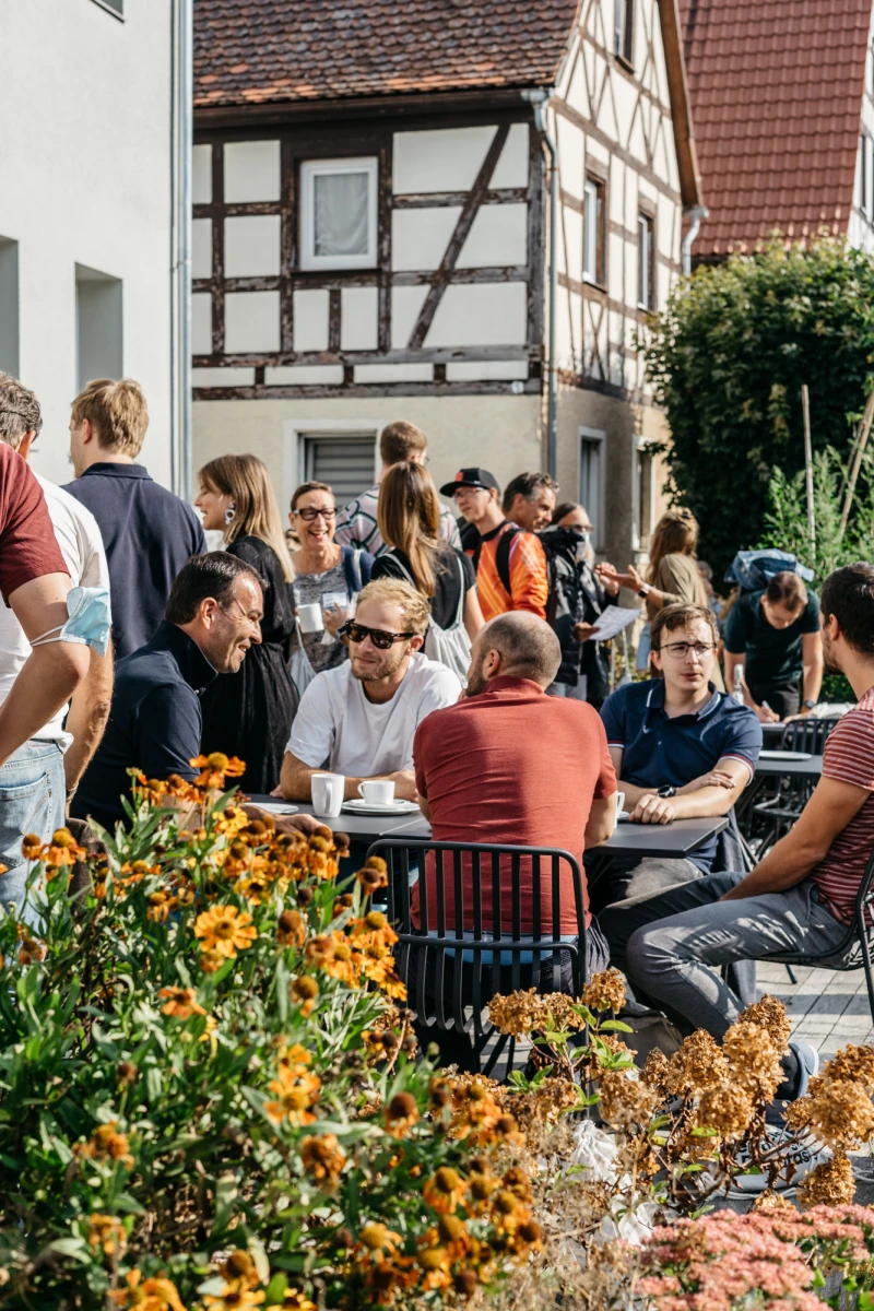 G&auml;ste genie&szlig;en Kaffee und Gespr&auml;che vor dem Schwarzen Adler.