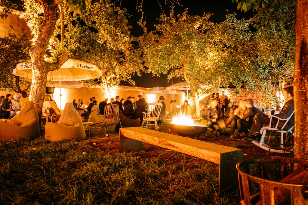 Gem&uuml;tliche Abendstimmung auf der Obstwiese des Gutshof Neun mit Feuerstelle und beleuchteten B&auml;umen.
