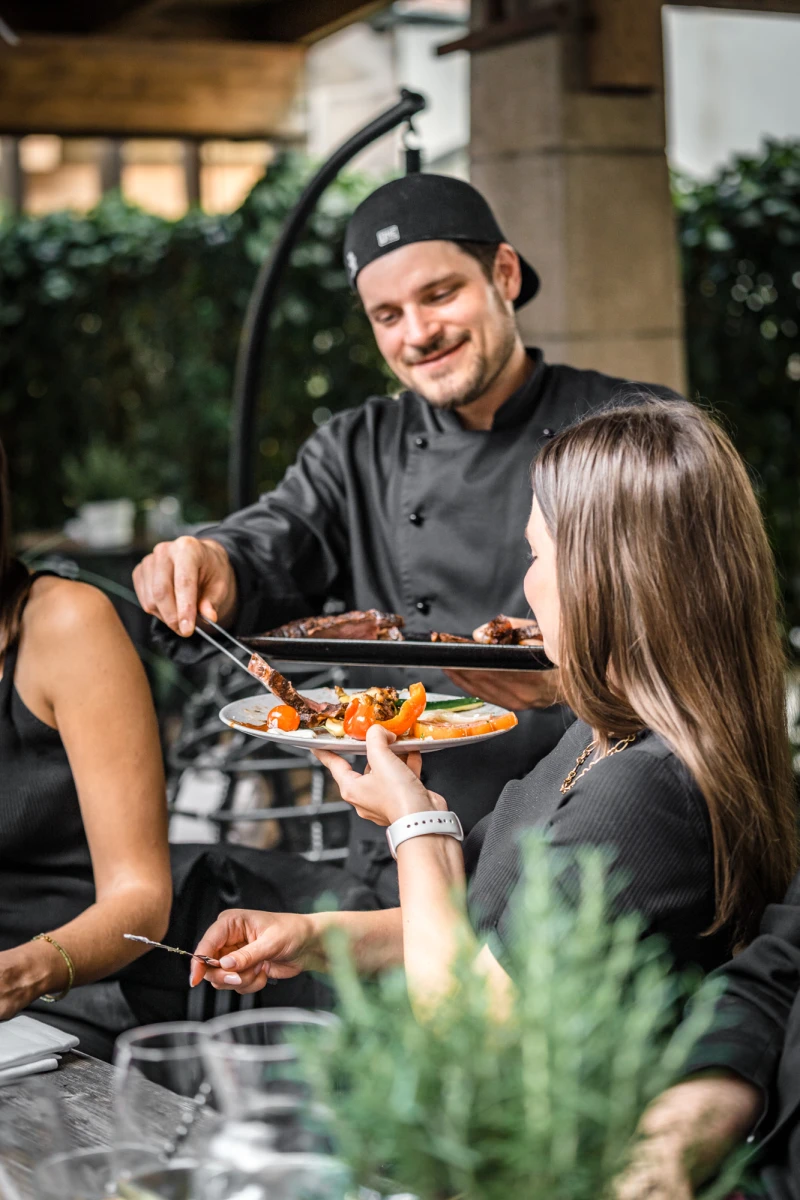 Koch serviert frische Grill-Speisen im Au&szlig;enbereich des Hotels.