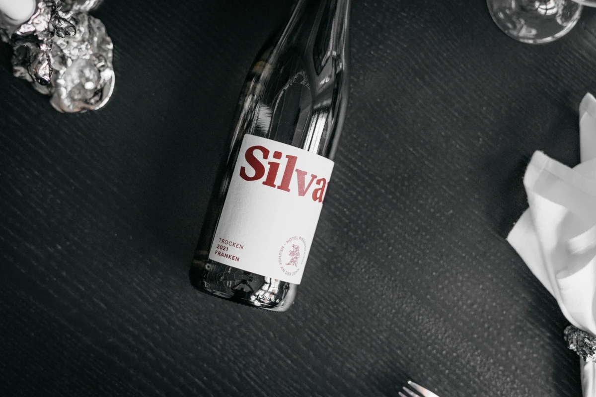 Schwarzwei&szlig;e Aufnahme einer Flasche Silva mit rotem Logo auf dunklem, strukturiertem Untergrund. Neben der Flasche sind verschwommen Kristalle oder Eisformen und ein wei&szlig;es Tuch zu erkennen.