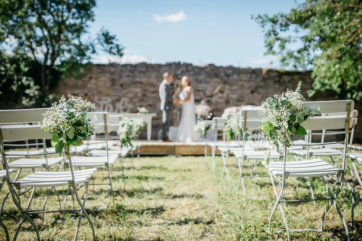 Hochzeit im Freien auf der Obstwiese im Gutshof Neun mit Blumen geschm&uuml;ckten St&uuml;hlen.